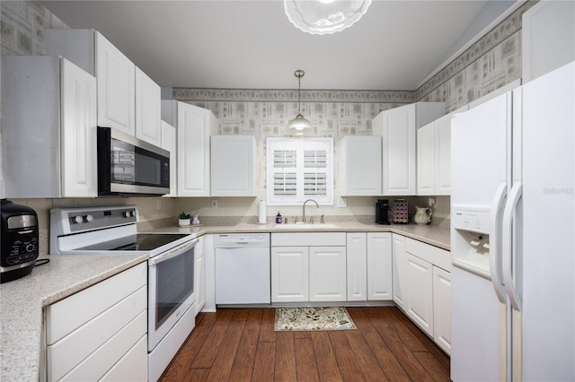 kitchen with sink, white cabinets, dark hardwood / wood-style flooring, hanging light fixtures, and white appliances