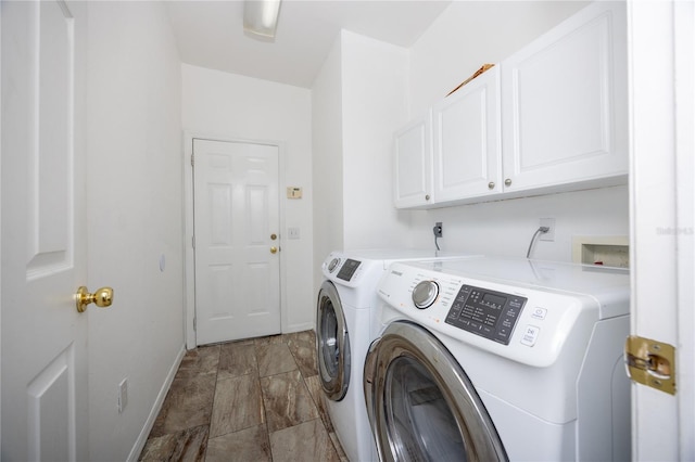 clothes washing area with washer and clothes dryer and cabinets