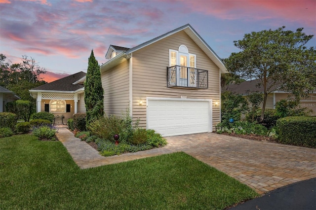 view of front of house featuring a yard, a garage, and a balcony