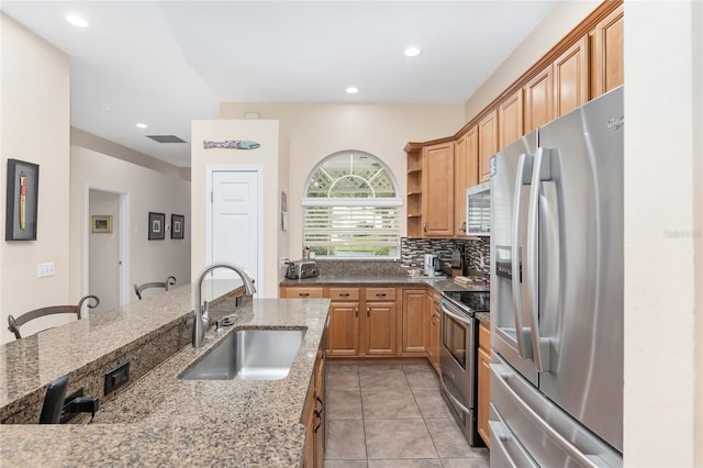 kitchen featuring appliances with stainless steel finishes, a breakfast bar, sink, backsplash, and light stone counters