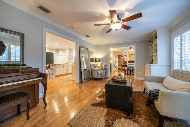 living area featuring light wood-style floors, visible vents, and ornamental molding