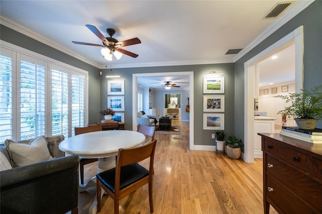 dining space with light wood-type flooring, baseboards, visible vents, and crown molding