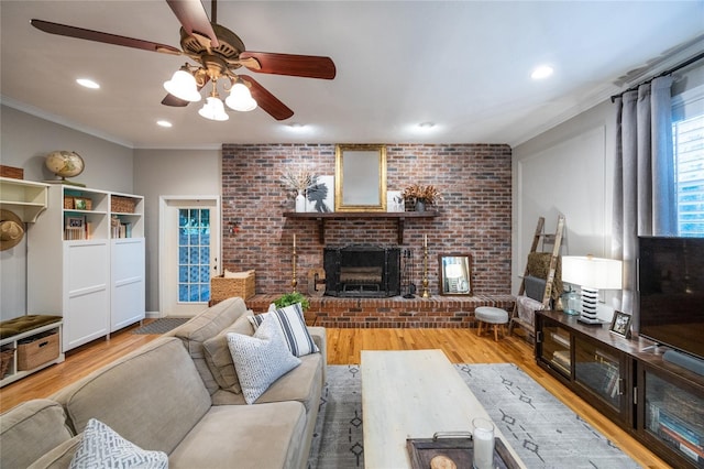 living area with a brick fireplace, crown molding, brick wall, and wood finished floors