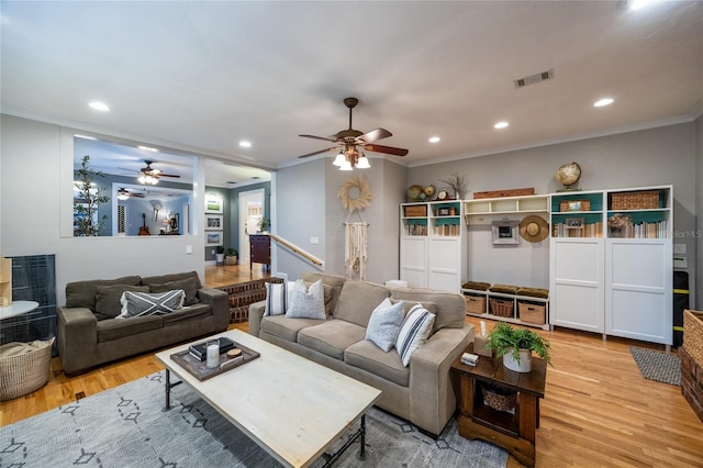 living area with light wood-style flooring, visible vents, crown molding, and recessed lighting