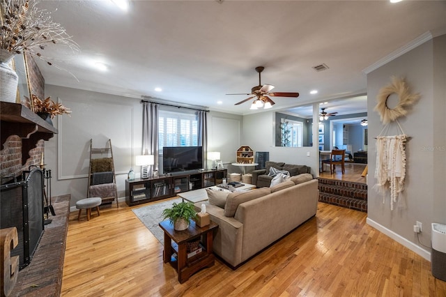 living room featuring a fireplace, visible vents, wood finished floors, and ornamental molding