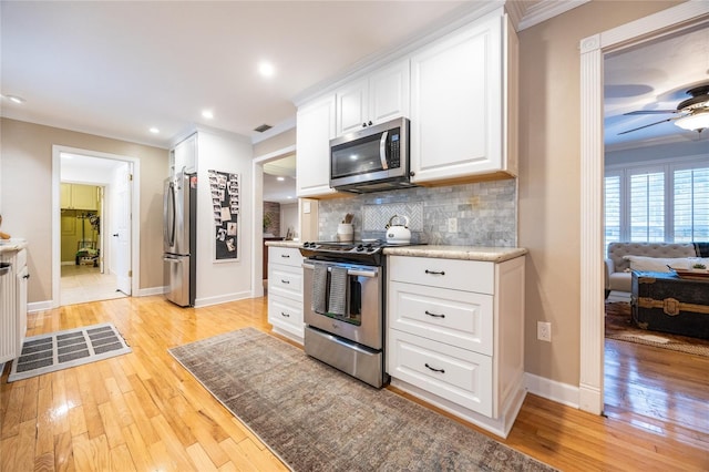 kitchen featuring white cabinets, decorative backsplash, light wood-style flooring, ornamental molding, and stainless steel appliances