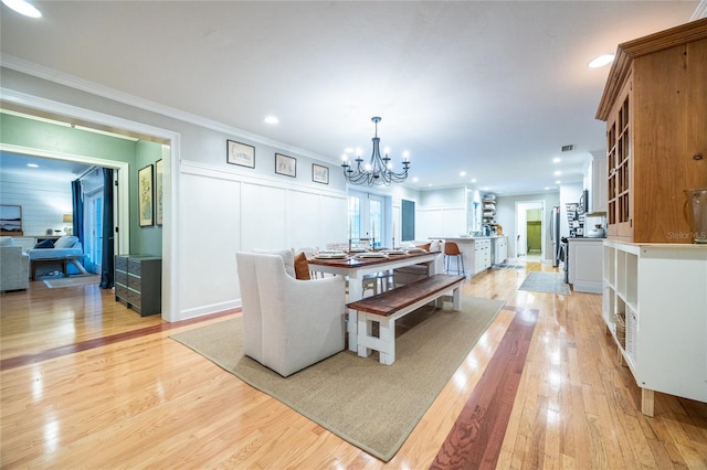 dining area with ornamental molding, light wood-type flooring, a notable chandelier, and recessed lighting