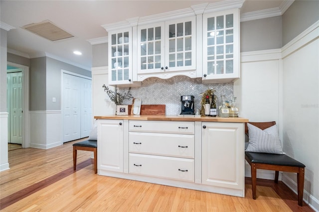 bar featuring ornamental molding, light wood-style flooring, visible vents, and tasteful backsplash