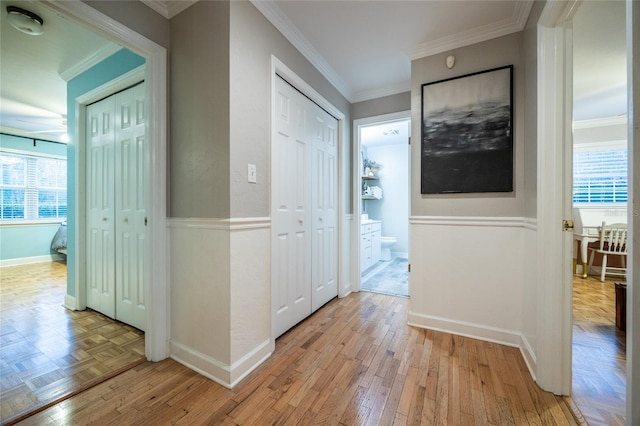 hallway with a wealth of natural light, crown molding, and parquet flooring