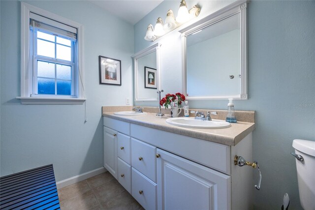 full bathroom featuring toilet, tile patterned flooring, double vanity, and a sink