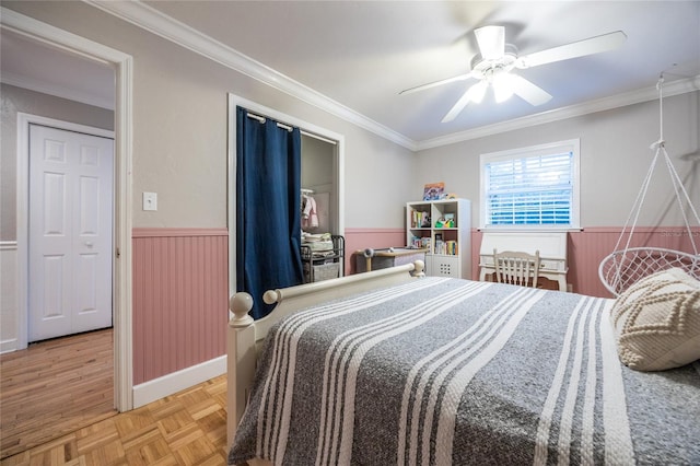 bedroom with wainscoting, a ceiling fan, and crown molding