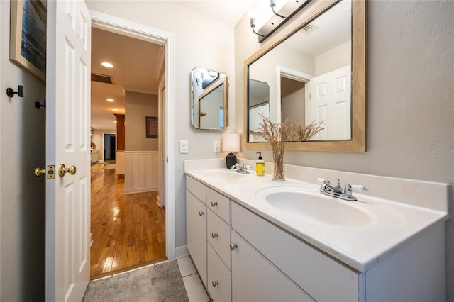 bathroom with double vanity, wood finished floors, wainscoting, and a sink