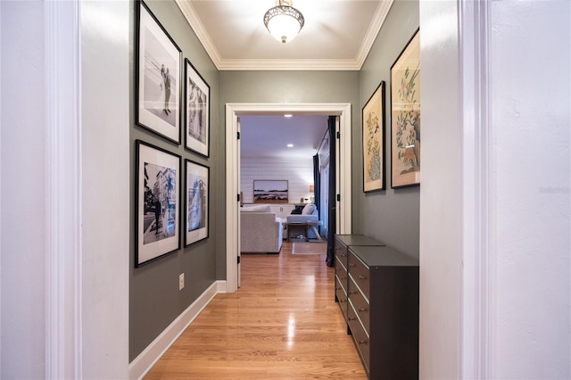 hallway with light wood-style floors, baseboards, and crown molding