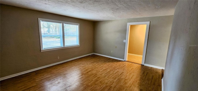 empty room with a textured ceiling and light hardwood / wood-style flooring