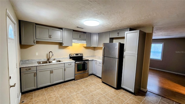 kitchen featuring sink, a textured ceiling, light tile patterned floors, gray cabinets, and stainless steel appliances