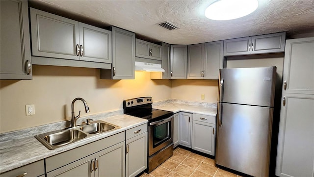 kitchen featuring gray cabinets, sink, light tile patterned floors, stainless steel appliances, and a textured ceiling