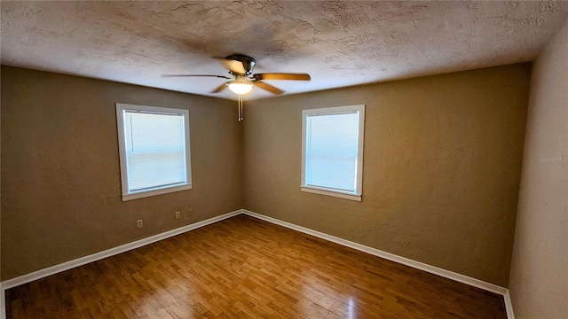 spare room with ceiling fan, plenty of natural light, hardwood / wood-style floors, and a textured ceiling