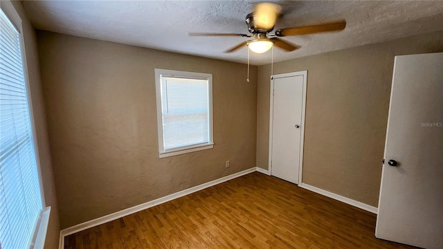 unfurnished bedroom featuring hardwood / wood-style flooring, a textured ceiling, ceiling fan, and a closet