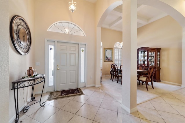 foyer with a high ceiling, coffered ceiling, light tile patterned floors, and beam ceiling