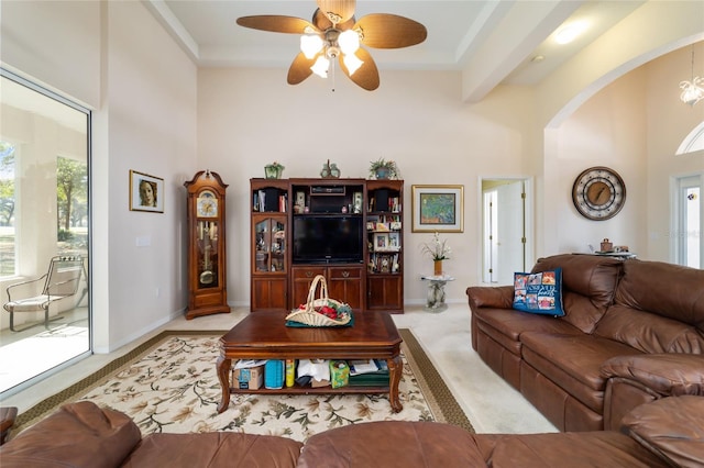 living room with beam ceiling, a towering ceiling, light colored carpet, and ceiling fan