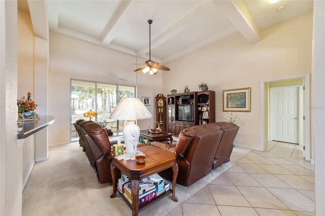 tiled living room featuring ceiling fan, beamed ceiling, and a high ceiling