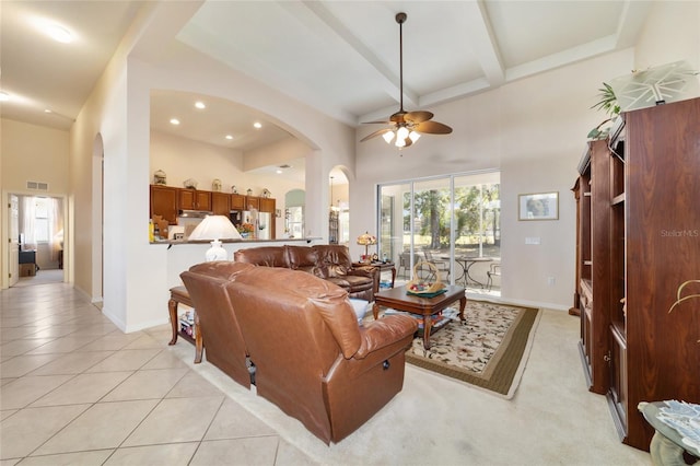 tiled living room featuring beam ceiling, ceiling fan, and a towering ceiling