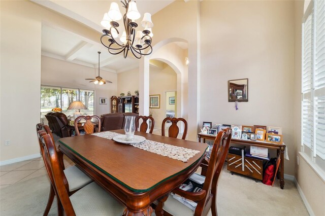 dining room with a high ceiling, light tile patterned flooring, ceiling fan with notable chandelier, and beamed ceiling