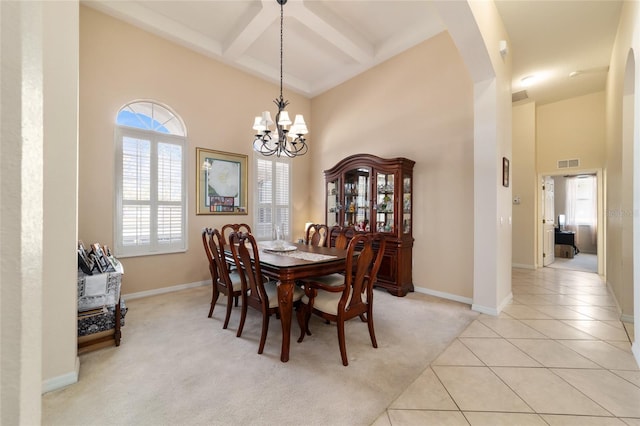 dining area featuring a towering ceiling, coffered ceiling, light tile patterned floors, a notable chandelier, and beam ceiling