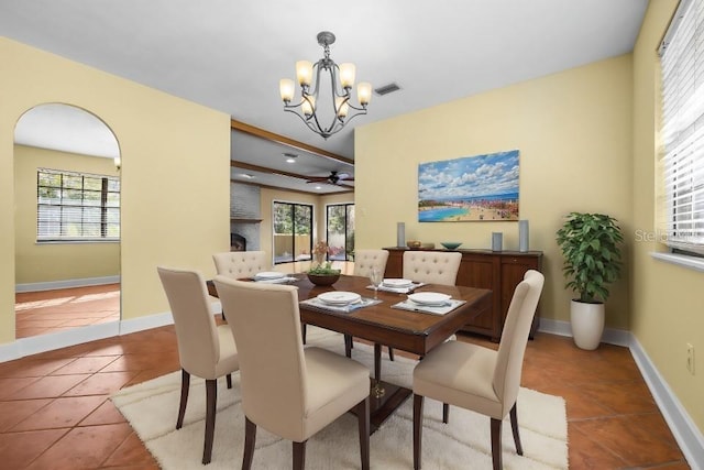 tiled dining area with a fireplace and a chandelier