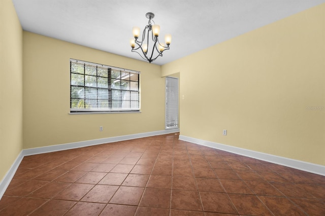 tiled spare room with an inviting chandelier