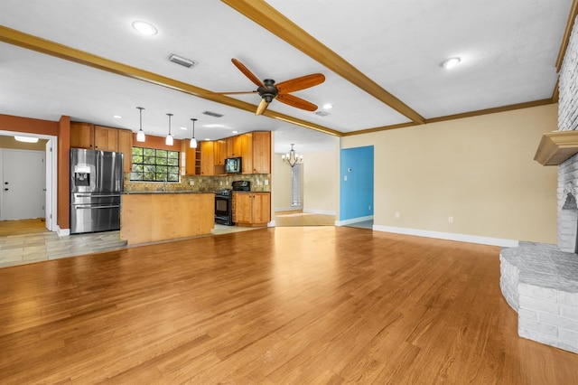 unfurnished living room with ceiling fan with notable chandelier, ornamental molding, a large fireplace, and light wood-type flooring