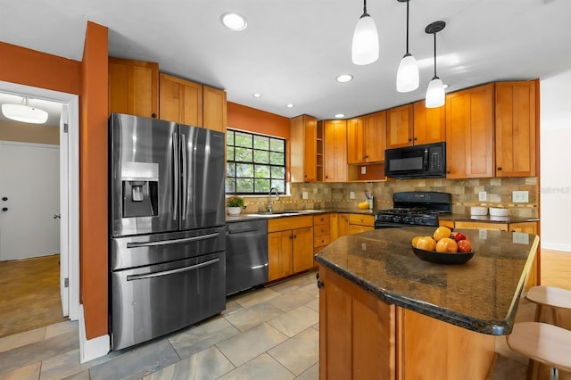 kitchen featuring a kitchen bar, sink, a center island, hanging light fixtures, and black appliances