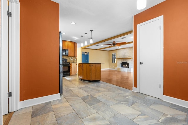 kitchen with decorative light fixtures, a brick fireplace, kitchen peninsula, ceiling fan, and black appliances