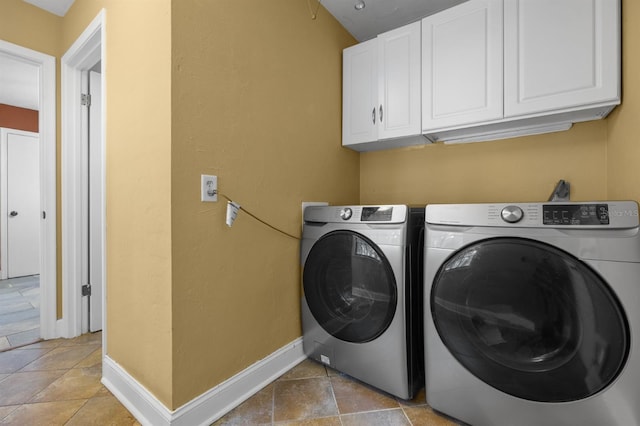 laundry room featuring cabinets, light tile patterned floors, and washing machine and clothes dryer