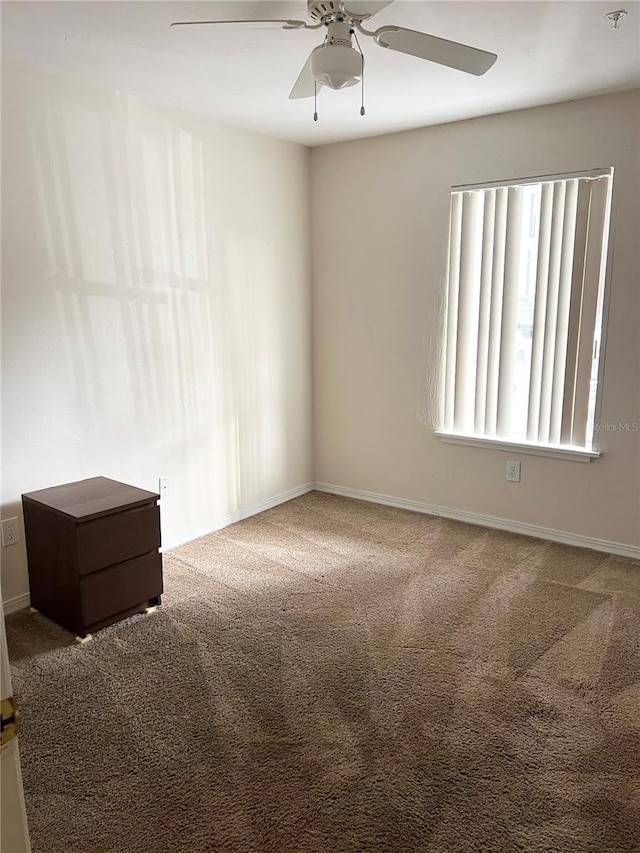 carpeted empty room with baseboards and a ceiling fan