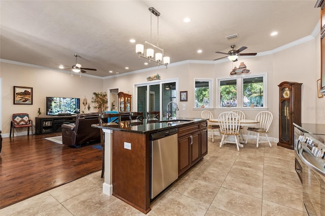 kitchen featuring pendant lighting, an island with sink, sink, light tile patterned floors, and stainless steel appliances