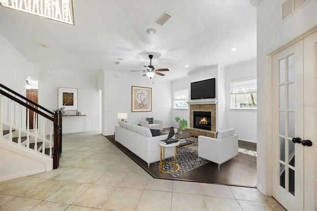 living room with light tile patterned floors, stairs, visible vents, and a tile fireplace