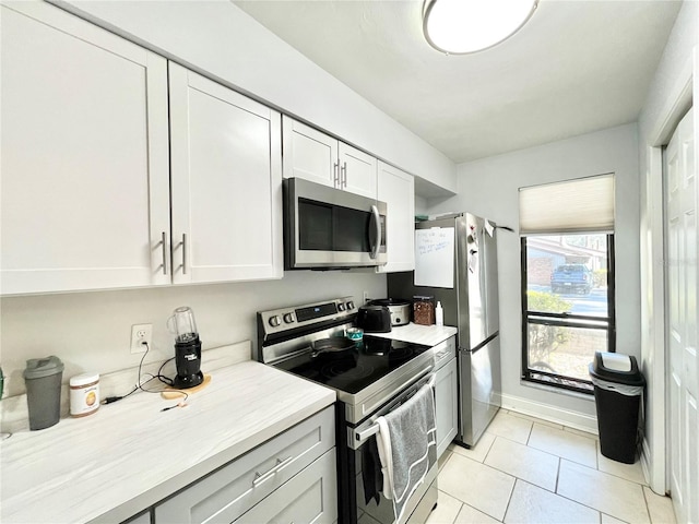 kitchen with white cabinets, appliances with stainless steel finishes, and light tile patterned floors