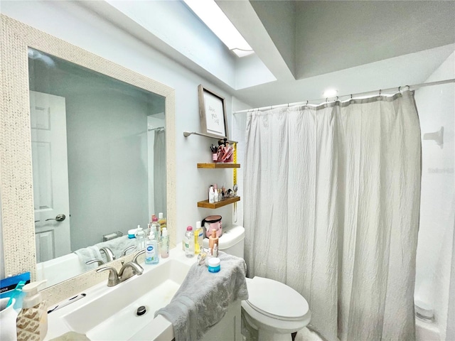 bathroom with a shower with curtain, toilet, a skylight, and sink