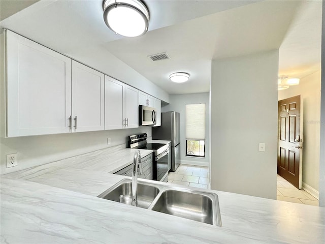 2820 NW 39th Ter, Gainesville, FL 32606 - kitchen featuring appliances with stainless steel finishes, light tile patterned floors, a sink, white cabinetry, and baseboards