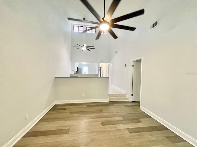 2820 NW 39th Ter, Gainesville, FL 32606 - unfurnished living room with ceiling fan, a high ceiling, baseboards, and wood finished floors