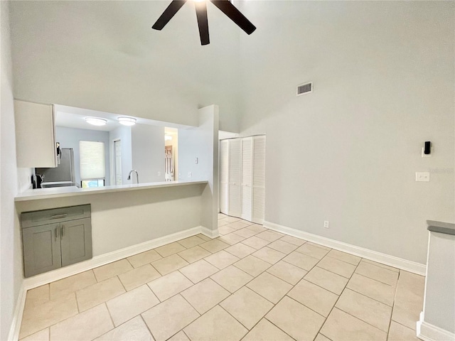 2820 NW 39th Ter, Gainesville, FL 32606 - unfurnished living room featuring a ceiling fan, light tile patterned floors, baseboards, and a high ceiling