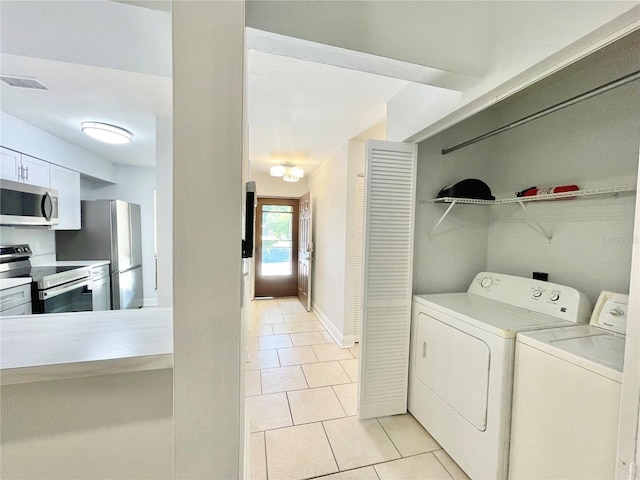 2820 NW 39th Ter, Gainesville, FL 32606 - laundry area featuring light tile patterned floors, washer and clothes dryer, and baseboards