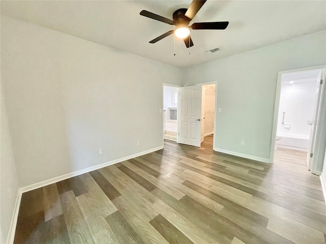 2820 NW 39th Ter, Gainesville, FL 32606 - unfurnished bedroom featuring wood finished floors, a walk in closet, ensuite bathroom, and baseboards