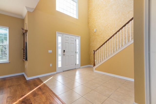 tiled foyer entrance featuring crown molding and a high ceiling