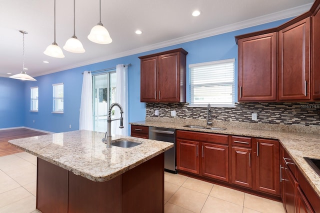 kitchen with a center island with sink, sink, stainless steel dishwasher, and decorative light fixtures