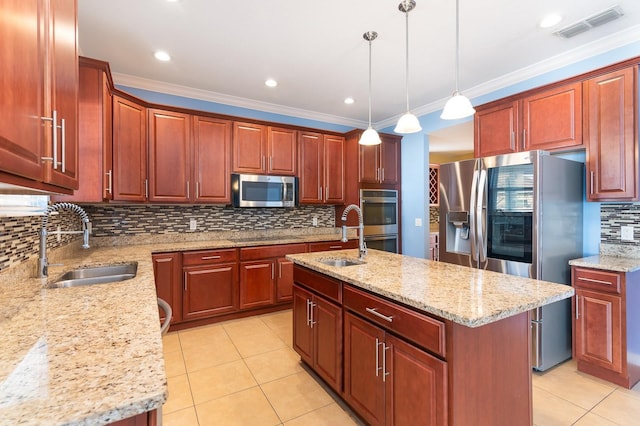 kitchen featuring appliances with stainless steel finishes, decorative light fixtures, light stone countertops, and a kitchen island with sink