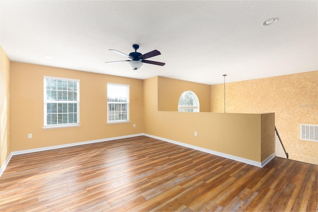 empty room with ceiling fan, hardwood / wood-style floors, and a textured ceiling