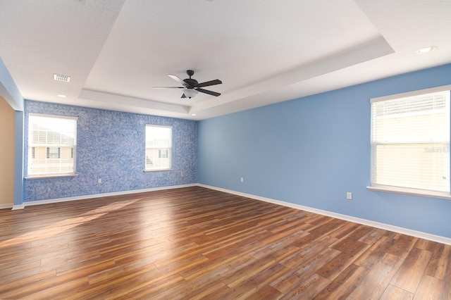 spare room with dark hardwood / wood-style floors, ceiling fan, and a tray ceiling