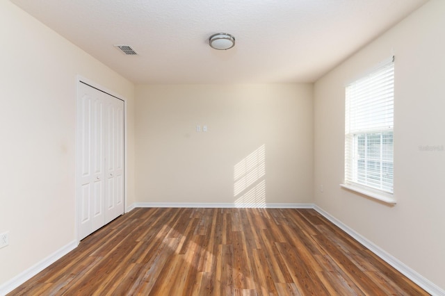 unfurnished bedroom featuring dark wood-type flooring and a closet